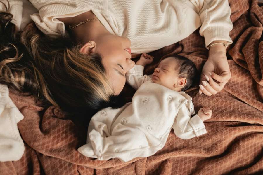 Une maman et son nouveau-né endormis blottis ensemble, illustrant l'importance du rituel du coucher.
